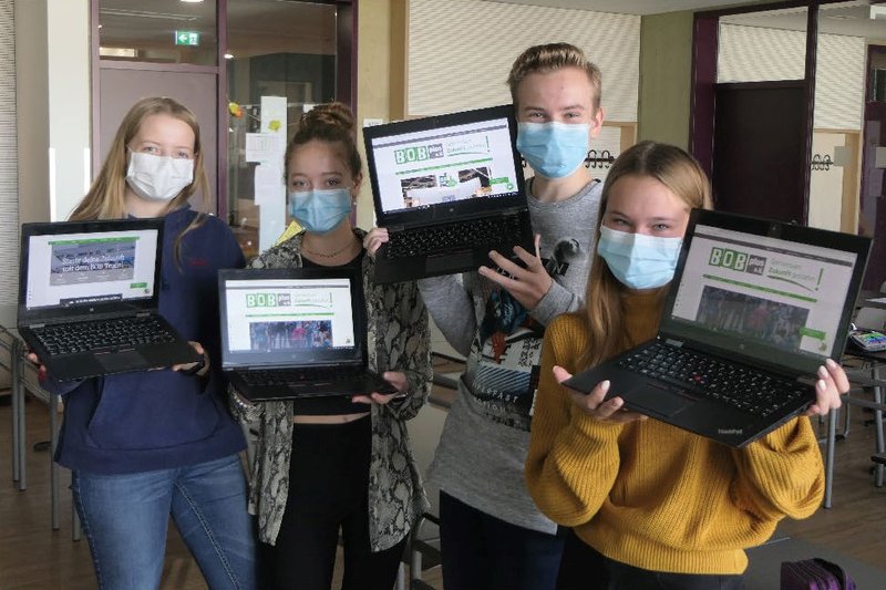 Vier SchülerInnen zeigen die Startseite der BOBplus e.V. Website auf ihren Laptops in die Kamera