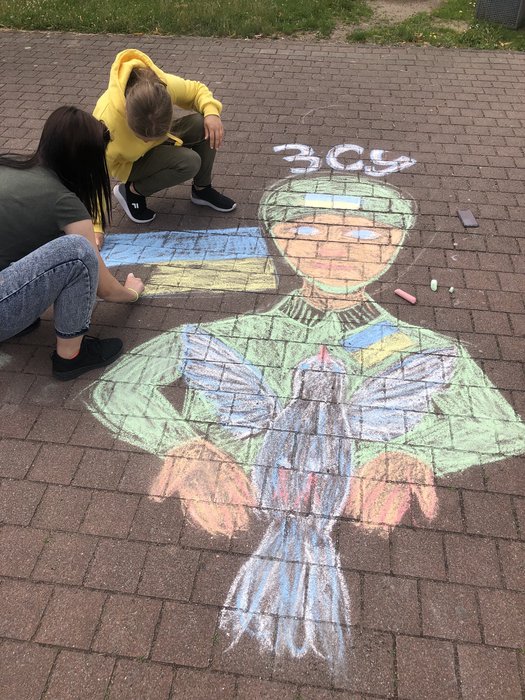 Schülerinnen malen mit Kreide Friedenstaube für die Ukraine auf den Boden